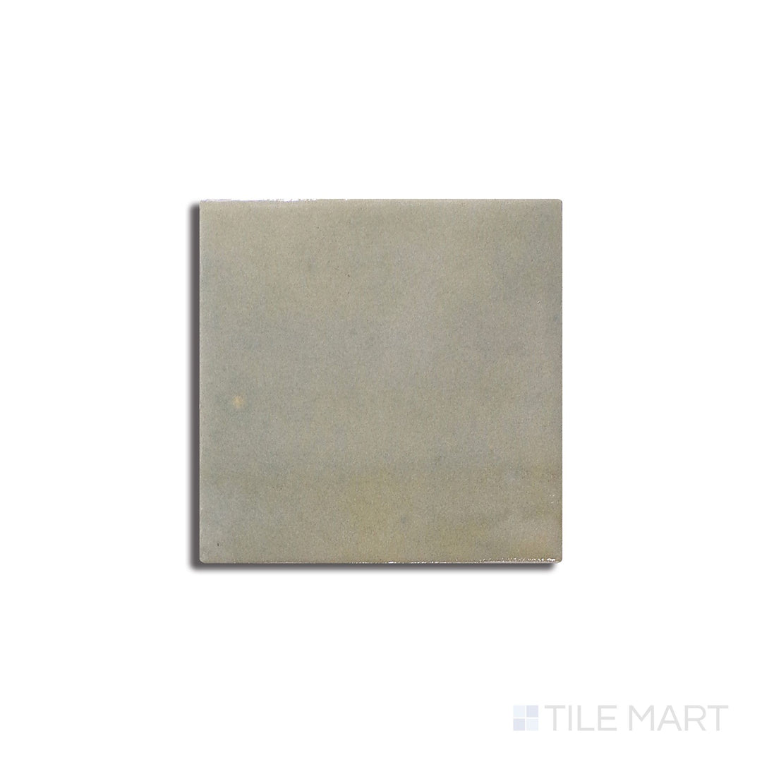 Angled shot of Zellige Neo Salvia 4x4 glossy glazed ceramic tile, featuring a rich sage green hue, a high-gloss reflective surface, and a handcrafted texture.  