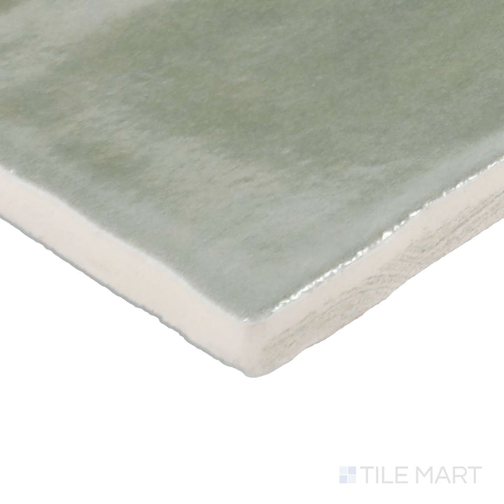 Corner shot of Zellige Neo Salvia 4X4 Glossy Glazed Ceramic Tile, showcasing its soft sage green tones with a handcrafted, high-gloss finish.