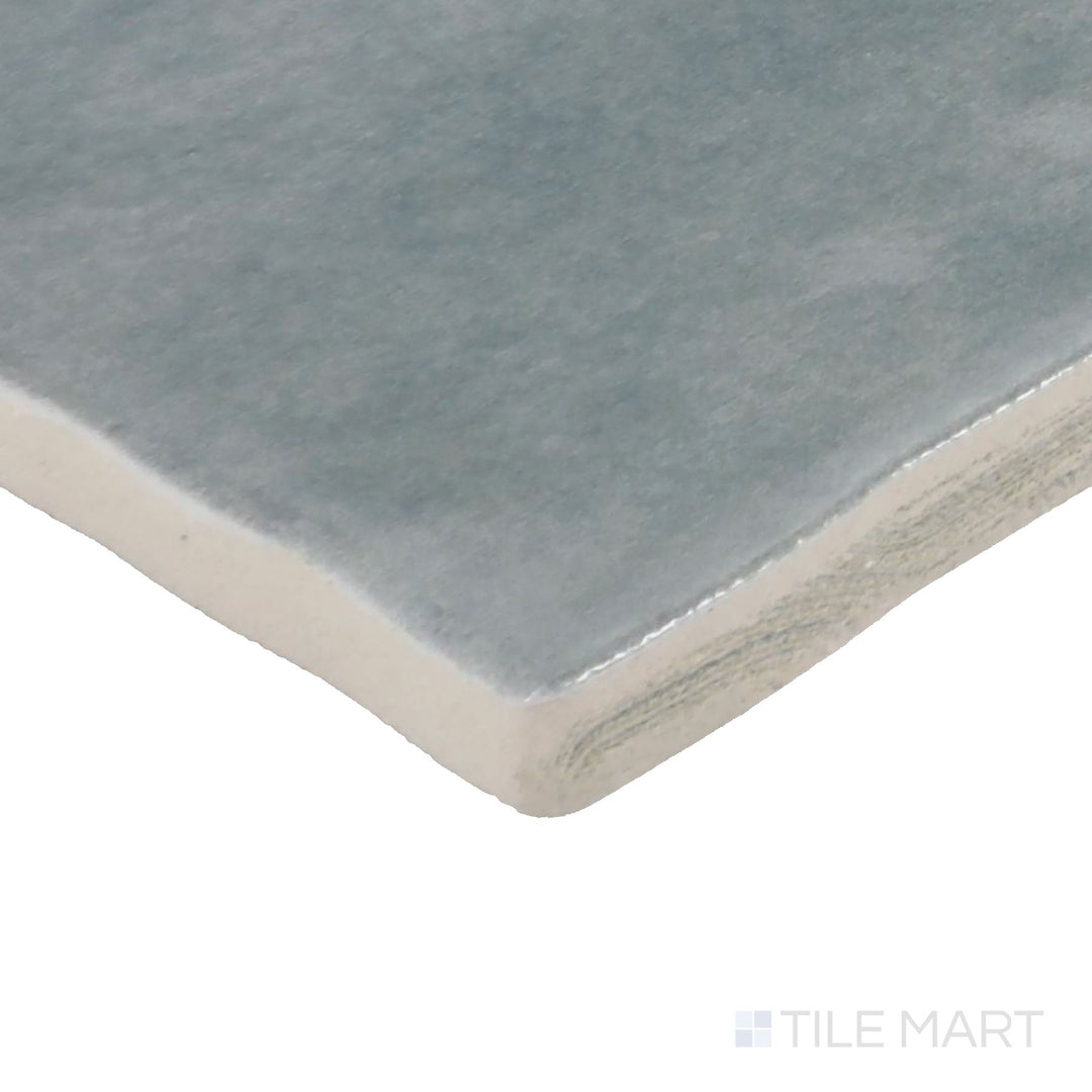 Angled view of Zellige Neo Cielo 4X4 Glossy Glazed Ceramic Tile, highlighting its serene sky-blue shade with a radiant, glossy surface.