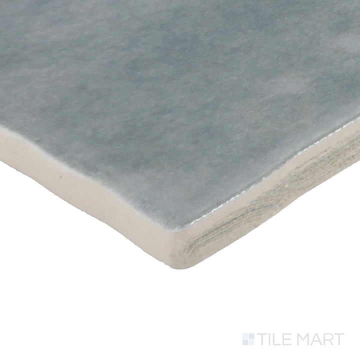 Angled view of Zellige Neo Cielo 4X4 Glossy Glazed Ceramic Tile, highlighting its serene sky-blue shade with a radiant, glossy surface.