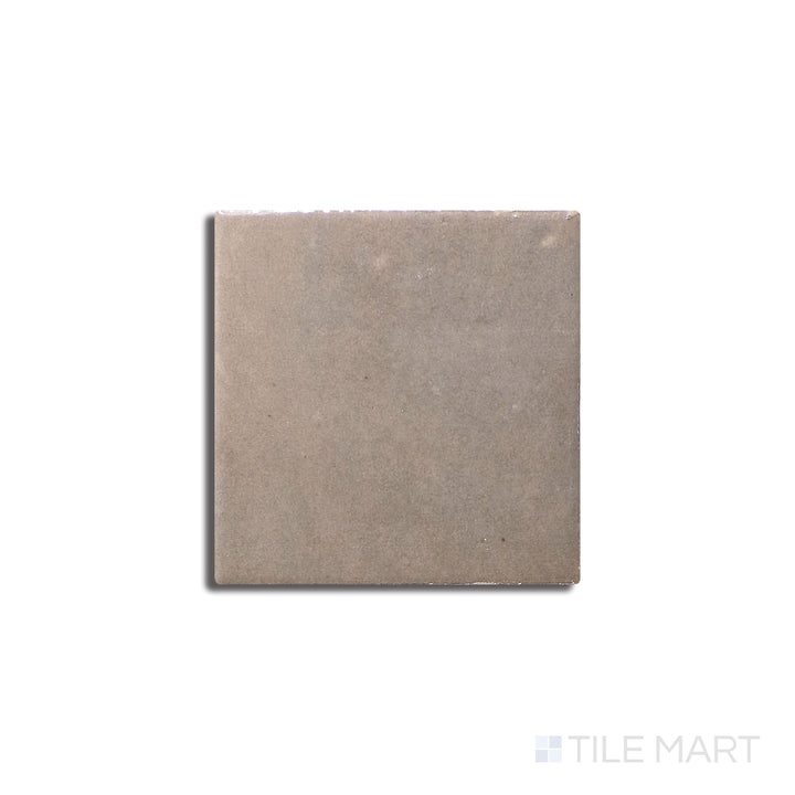 Slanted perspective of Zellige Neo Lana 4x4 glossy glazed ceramic tile, emphasizing its warm beige color, subtle variations in tone, and a high-gloss glazed finish.  