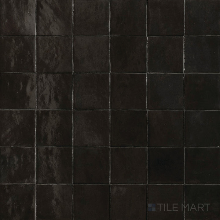 Top-down view of Zellige Neo Carbone 4x4 glossy glazed ceramic tile, showcasing deep tone and handcrafted surface variation.