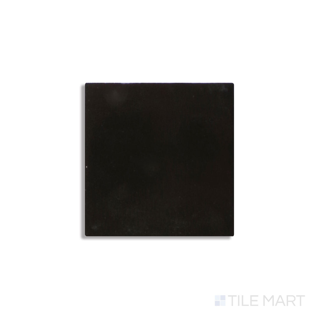 Angled view of Zellige Neo Carbone 4x4 glossy glazed ceramic tile reveals rich dark tone and reflective handcrafted surface.