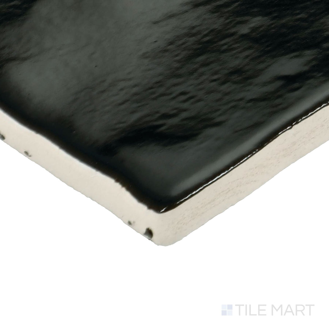 Corner shot of Zellige Neo Carbone 4x4 glossy glazed ceramic tile showing edge depth and dark, reflective surface variation.