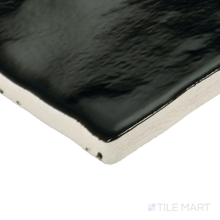 Corner shot of Zellige Neo Carbone 4x4 glossy glazed ceramic tile showing edge depth and dark, reflective surface variation.