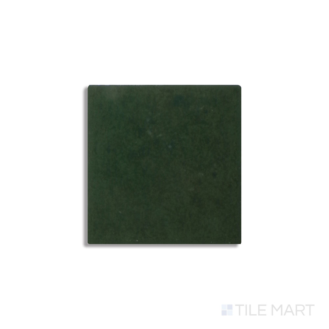 Diagonal view of Zellige Neo Bosco 4x4 glossy glazed ceramic tile, showcasing a deep forest green hue, a striking glossy finish, and natural tonal variations.  
