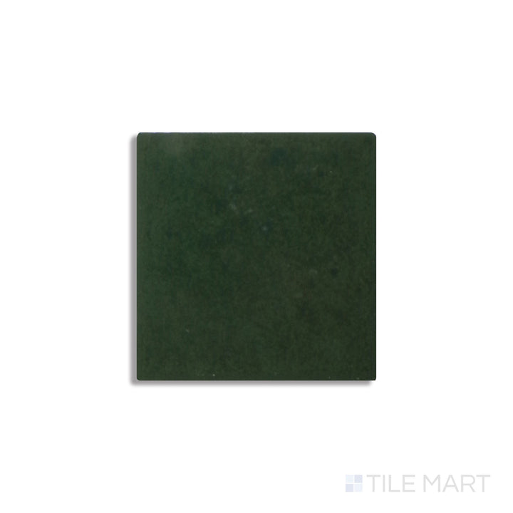 Diagonal view of Zellige Neo Bosco 4x4 glossy glazed ceramic tile, showcasing a deep forest green hue, a striking glossy finish, and natural tonal variations.  