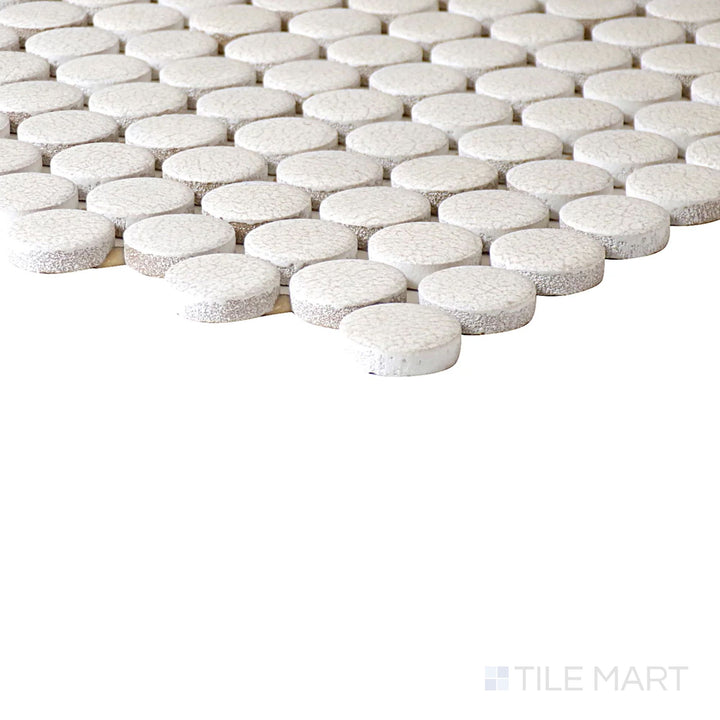 Angled close-up of Inyo Crema Penny Round Matte Glazed Ceramic Mosaic, showcasing its delicate cream tones with a playful penny-round layout.