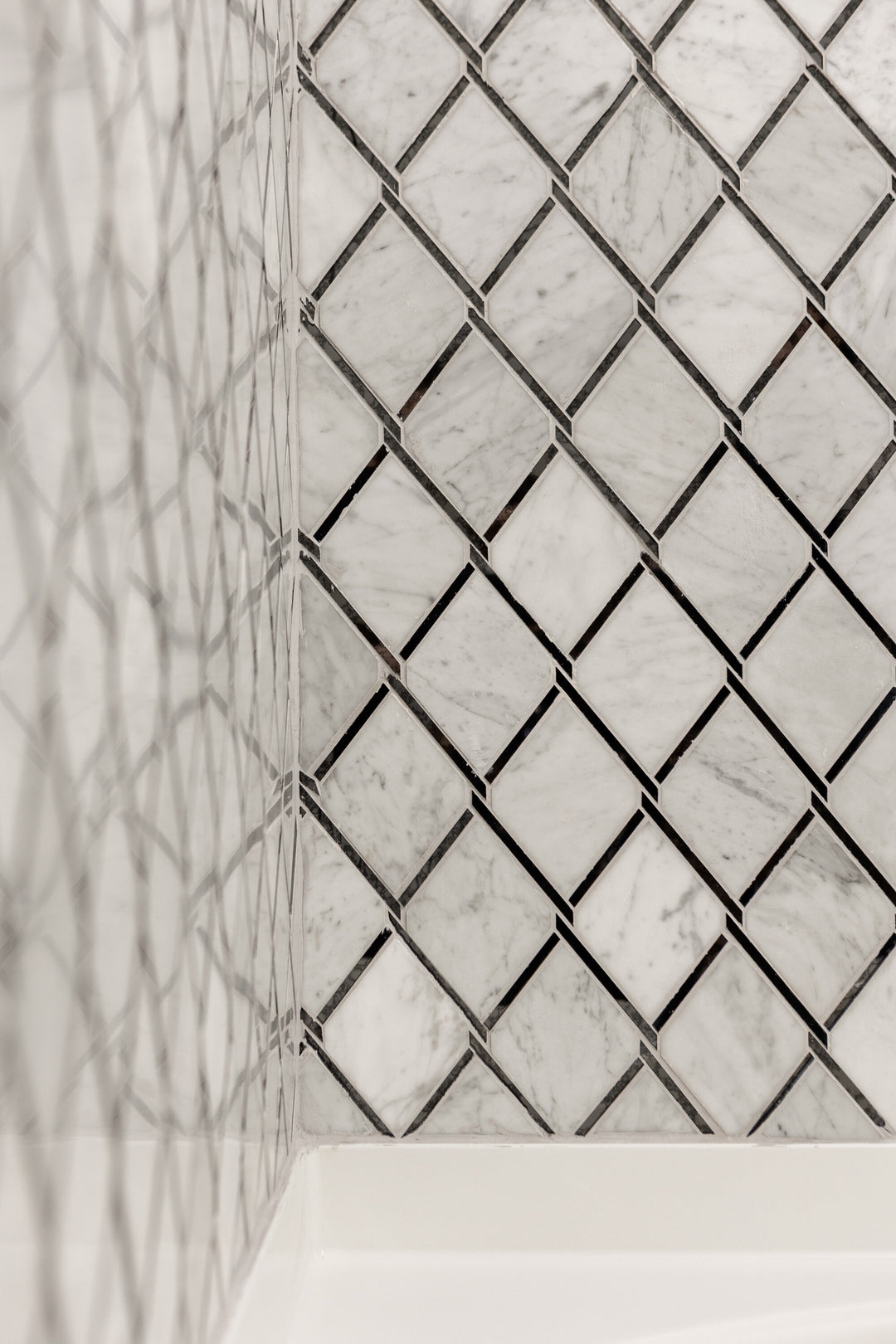 Displayed in a real-world installation, the Lavaliere Carrara White and black antique mirror chain link polished mosaic introduces bold pattern and shine