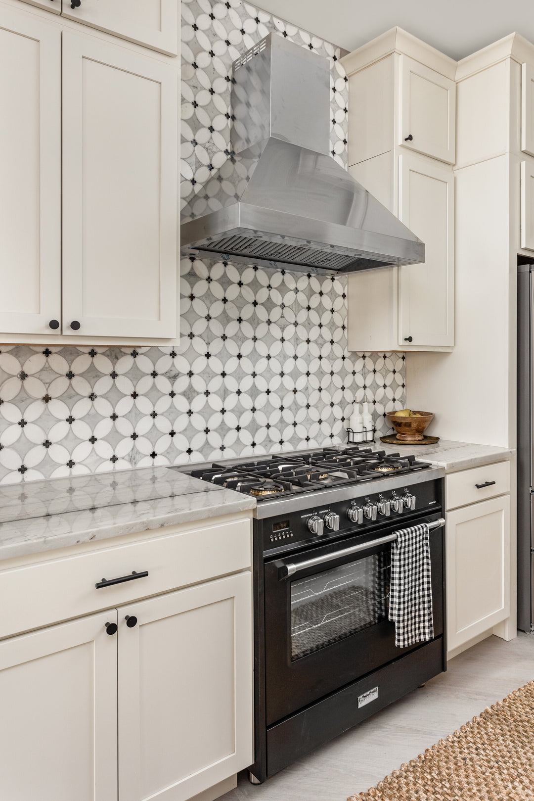 Used in an interior environment, the Lavaliere Carrara, Thassos, and black antique mirror petal honed mosaic adds soft geometry and layered texture