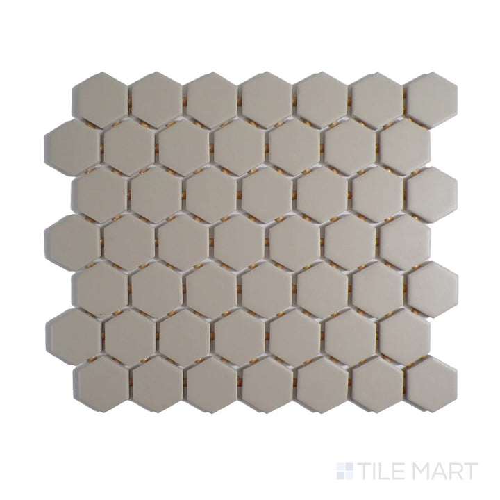 Diagonal view of Color Wheel Mosaic Urban Putty 1.5" hexagon glossy glazed ceramic tile, featuring a neutral beige-gray shade with a polished surface in a structured hexagonal design.  