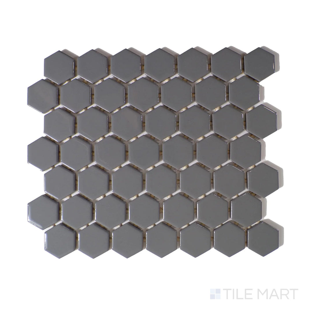 Angled shot of Color Wheel Mosaic Suede Gray 1.5" hexagon glossy glazed ceramic tile, showcasing a muted gray tone with a polished texture in a geometric hexagonal layout.  