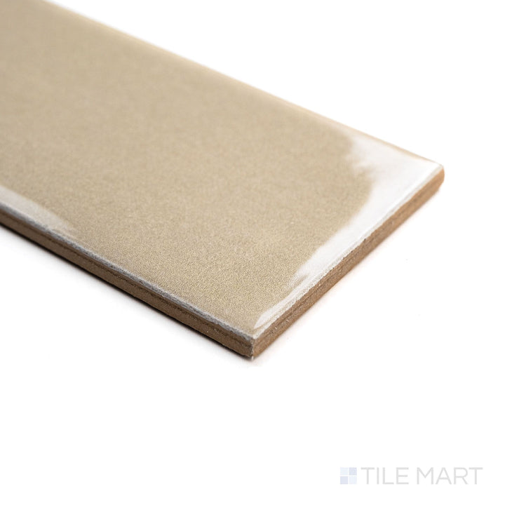 Angled shot of Canvas Sago Pearl 3x10 Glossy Ceramic Tile showcasing its creamy off-white tone and lustrous surface with natural light reflections.