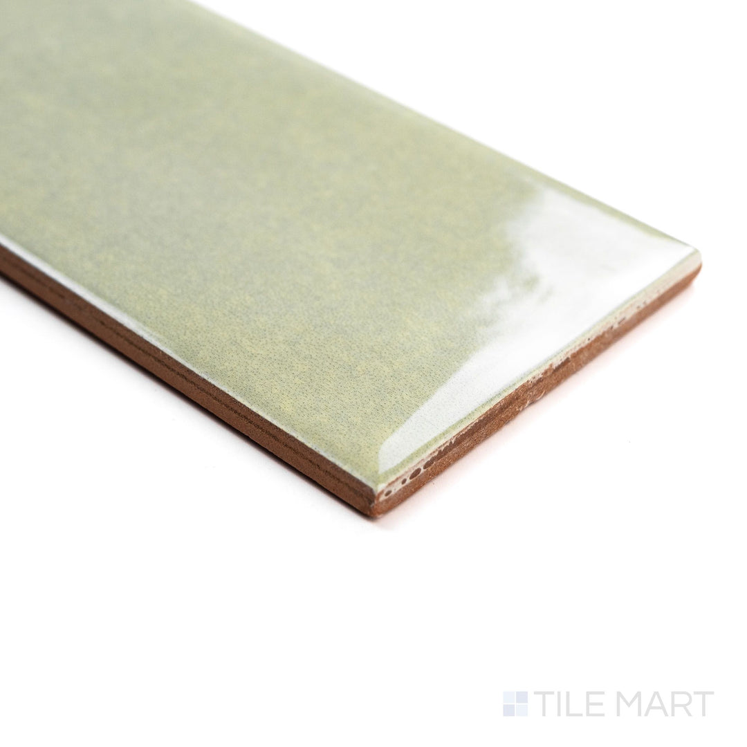Canvas Green Tea 3x10 Glossy Ceramic Tile in a corner view, highlighting its earthy green color and glossy finish with soft angled depth.