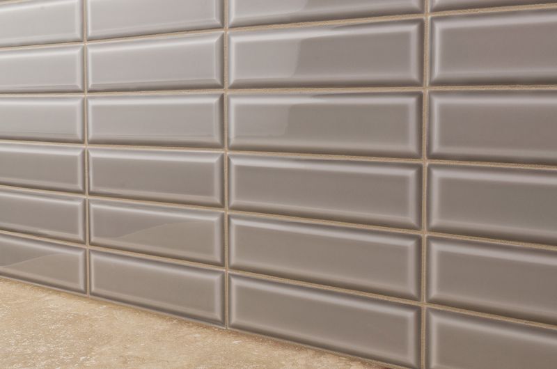 A stylish interior featuring Boutique Sleek Fossil 3x9 beveled glossy ceramic tiles, adding a refined touch with their neutral hue and sleek reflective surface.