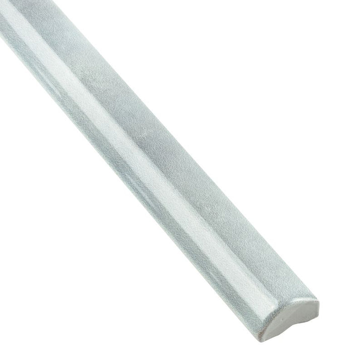 A corner shot of Moroccan Habitat Misty 1x12 glossy ceramic pencil trim, emphasizing its sleek, rounded shape and reflective surface.