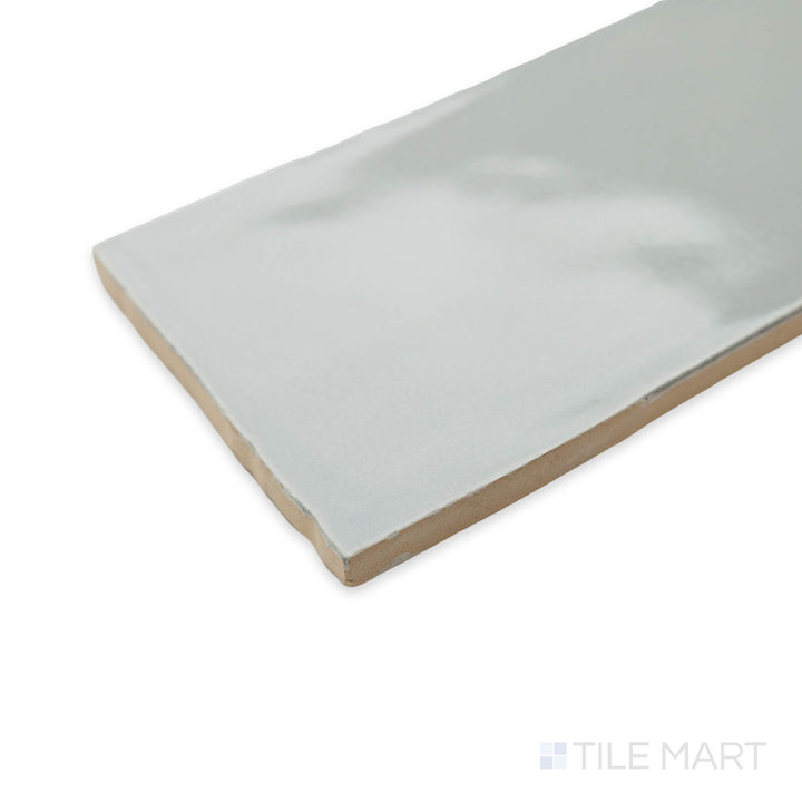 Corner view of Artesano Neu Gray 3X12 bright ceramic tile, emphasizing its neutral gray tone, glossy surface, and the structured formation at the edges.