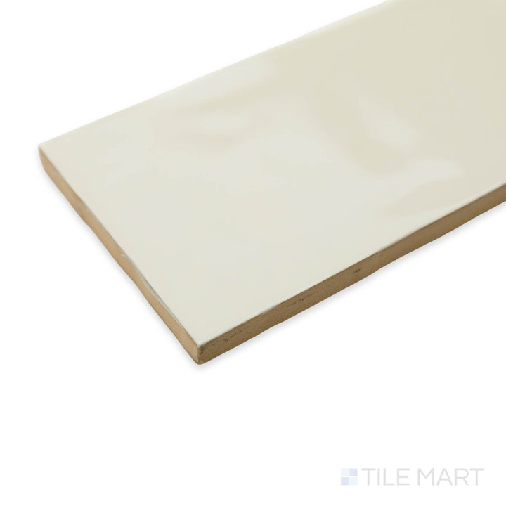 Side-angle perspective of Artesano Biscuit 3X12 bright ceramic tile, highlighting its soft beige tone, reflective surface, and smooth corner transition.
