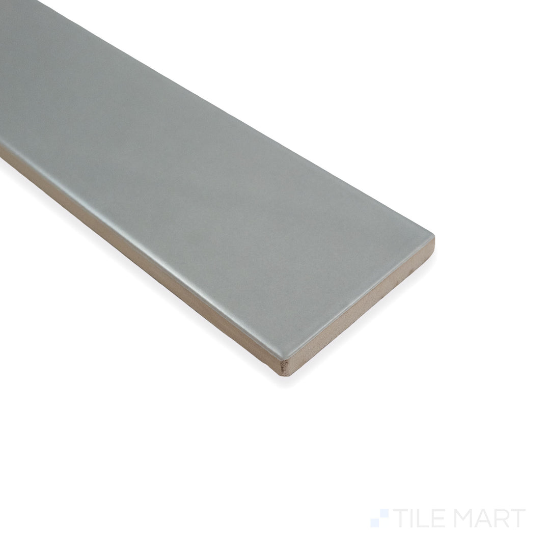 Angled perspective of Block Gris 2X10 bright ceramic tile, emphasizing its smooth light-gray sheen, reflective texture, and structured tile layout at the corner.