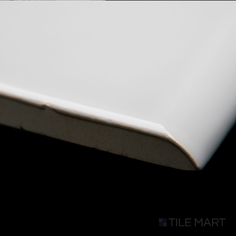 A close-up corner shot of Block Gris 2x10 bright ceramic bullnose, highlighting its smooth edges, sleek gray tone, and glossy finish.