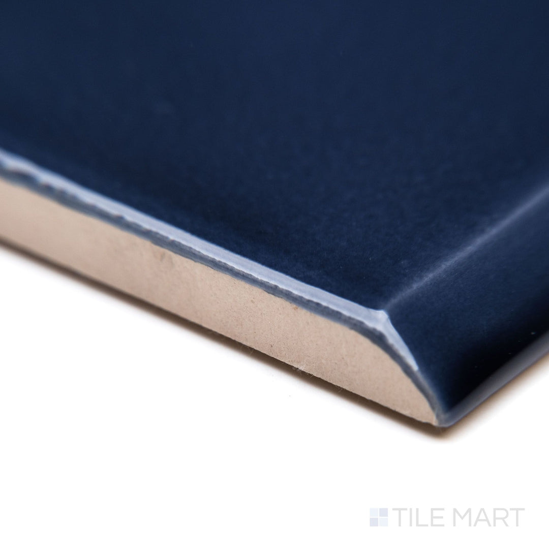 A close-up of Block Azul 2x10 bright ceramic bullnose, capturing its deep blue shade, curved bullnose edge, and lustrous glossy texture.