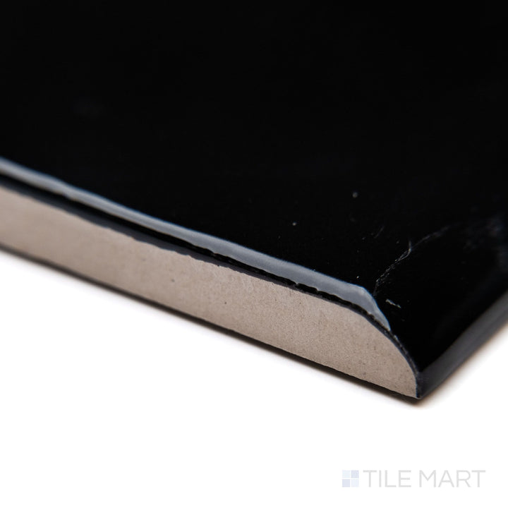 A close-up of Block Negro 2x10 bright ceramic bullnose, highlighting its deep black shade, well-defined bullnose edge, and glossy ceramic finish.