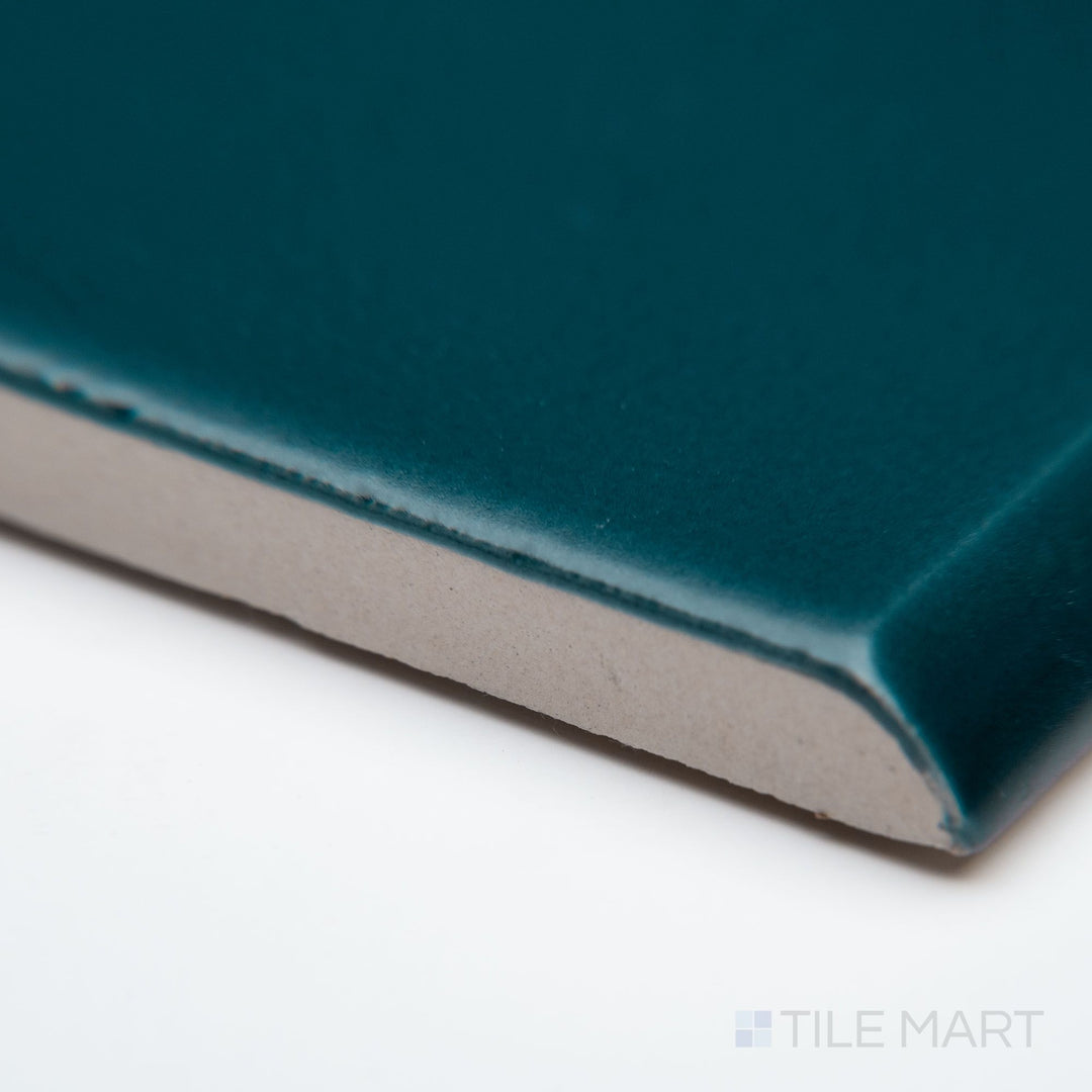A zoomed-in corner shot of Block Verde 2x10 matte ceramic bullnose, focusing on its muted green shade, rounded profile, and soft matte texture.