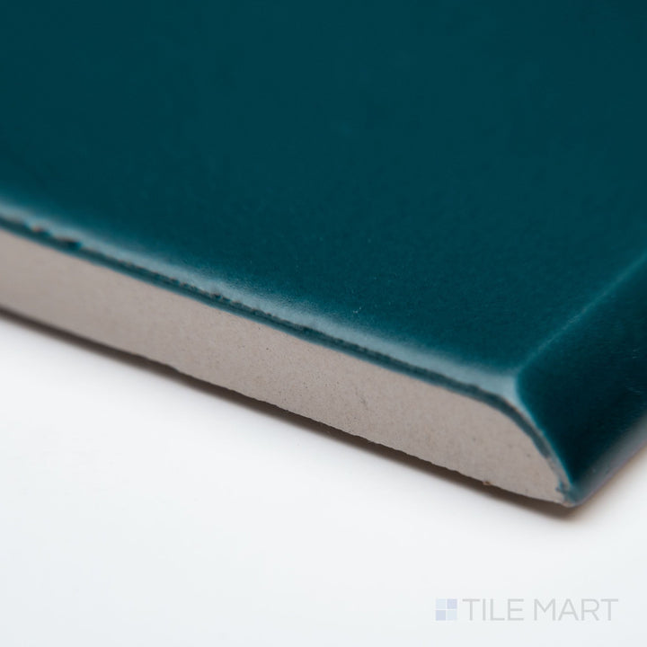 A zoomed-in corner shot of Block Verde 2x10 matte ceramic bullnose, focusing on its muted green shade, rounded profile, and soft matte texture.