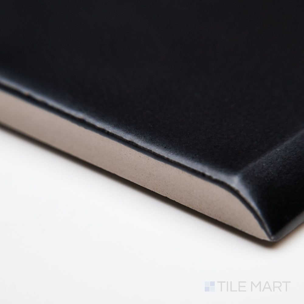 A close-up edge view of Block Negro 2x10 matte ceramic bullnose, emphasizing its bold black color, curved bullnose edge, and velvety matte finish.