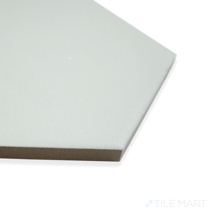 Angled view of Block Gris 6" hexagon matte glazed porcelain tile, showcasing its neutral gray shade, soft matte glaze, and sharp hexagonal edge meeting at the corner.