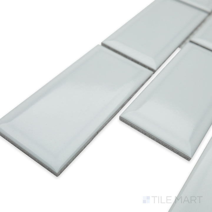 Angled view of Cc Mosaics Plus White Ice 2X4 beveled bright glazed porcelain tile, featuring its elegant beveled edges, luminous white finish, and well-defined corner alignment.