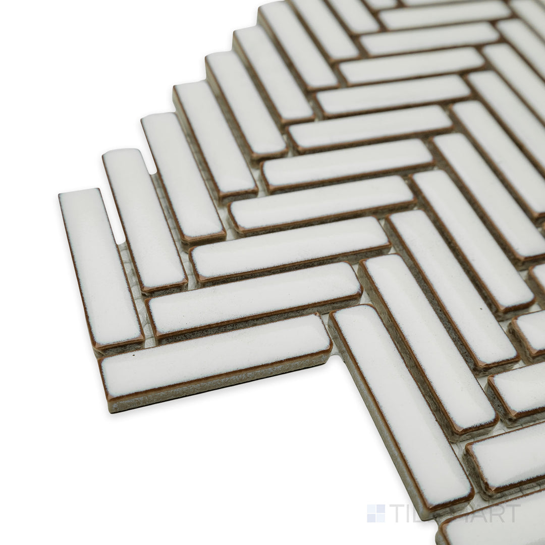 Close-up corner perspective of Cc Mosaics Plus Antique White herringbone bright glazed porcelain tile, highlighting its off-white tone, intricate herringbone pattern, and glossy surface.