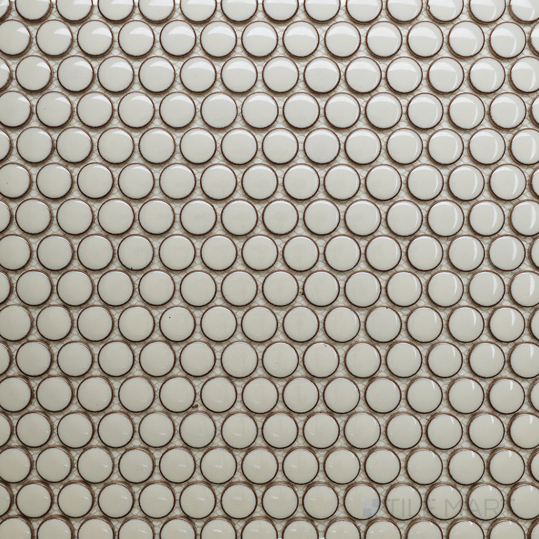 Seen from above, the Cc Mosaics Plus Cream Penny Round bright glazed porcelain tile reveals a soft cream shade with a smooth, glossy finish, adding warmth and elegance to any space.