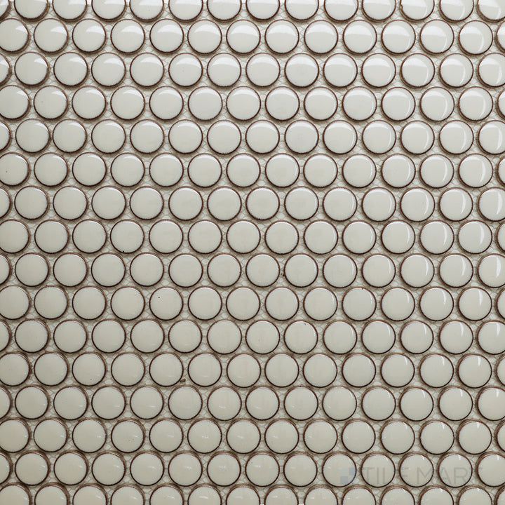 Seen from above, the Cc Mosaics Plus Cream Penny Round bright glazed porcelain tile reveals a soft cream shade with a smooth, glossy finish, adding warmth and elegance to any space.