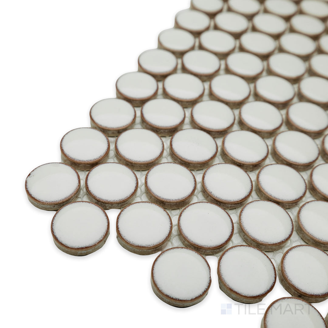 Angled view of Cc Mosaics Plus Cream penny round bright glazed porcelain tile, featuring its soft cream tone, round mosaic shape, and polished surface.