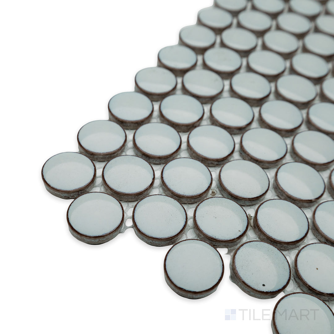 Side-angle close-up of Cc Mosaics Plus Mint Green penny round bright glazed porcelain tile, showcasing its fresh green hue, circular mosaic layout, and glossy sheen.