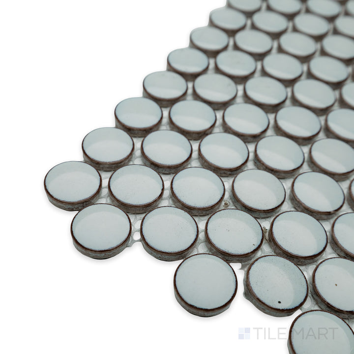 Side-angle close-up of Cc Mosaics Plus Mint Green penny round bright glazed porcelain tile, showcasing its fresh green hue, circular mosaic layout, and glossy sheen.