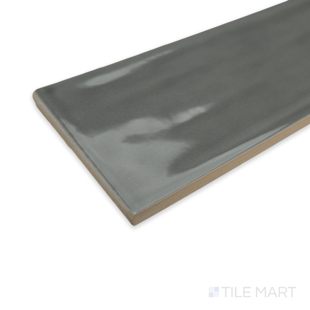 Angled perspective of Flow Dark Gray 3X12 bright ceramic tile, highlighting its deep charcoal shade, polished surface, and sharp edge definition.