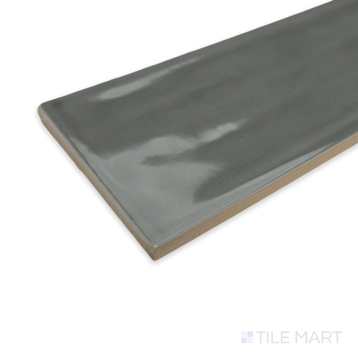Angled perspective of Flow Dark Gray 3X12 bright ceramic tile, highlighting its deep charcoal shade, polished surface, and sharp edge definition.