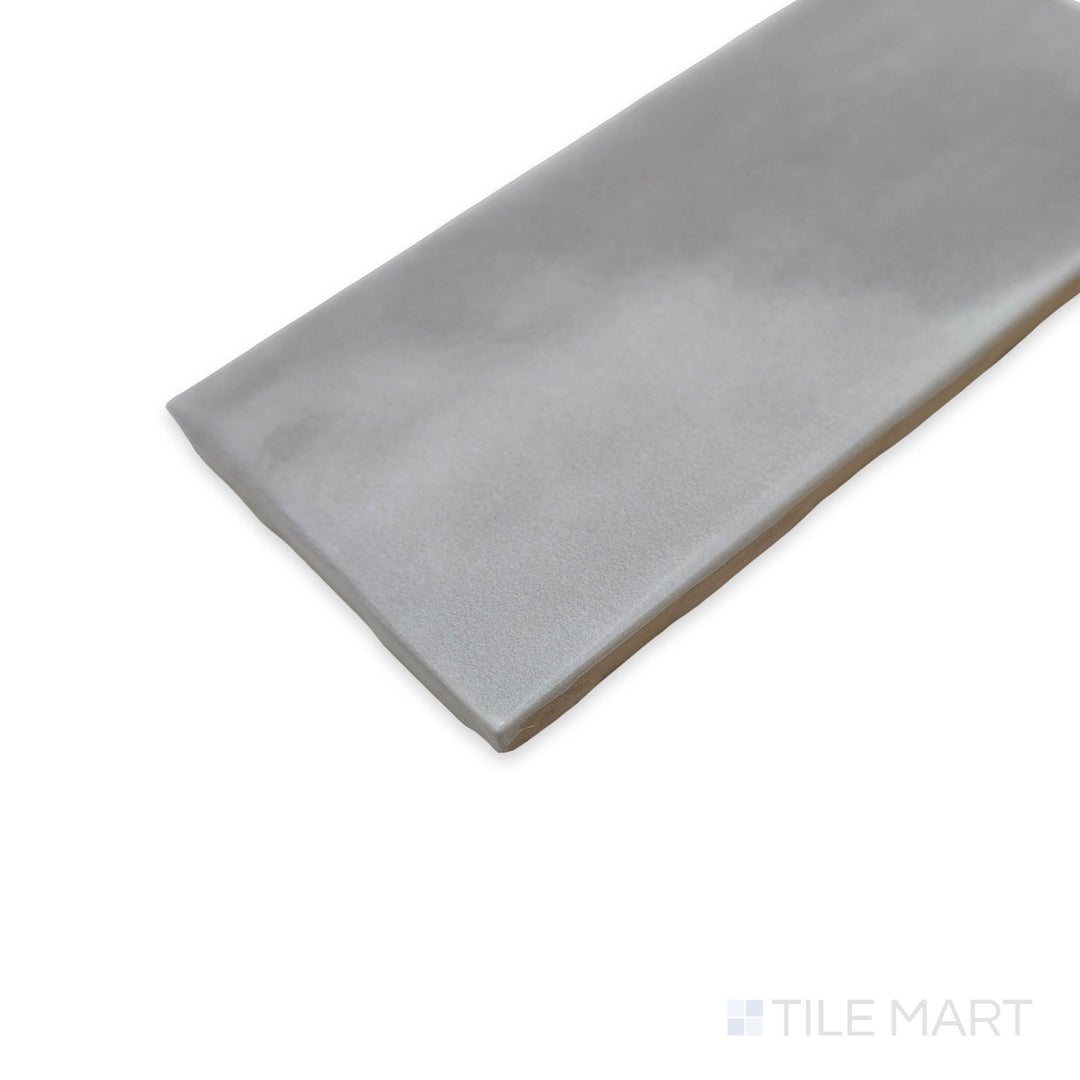 A close-up corner image of the Maiolica Tender Gray 3x6 bright ceramic tile highlights its smooth, neutral shade and high-gloss coating, perfect for contemporary designs.