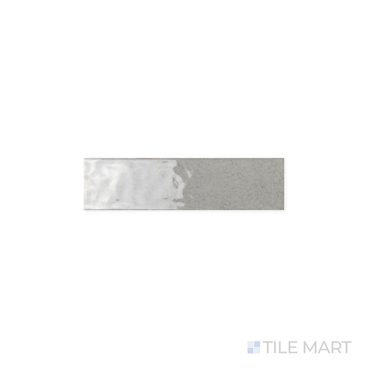 A close-up view of Maiolica Tender Gray 3x12 Bright Ceramic Tile, showcasing its polished surface and soft gray tone. The glossy finish enhances light reflection for a refined, sleek look.