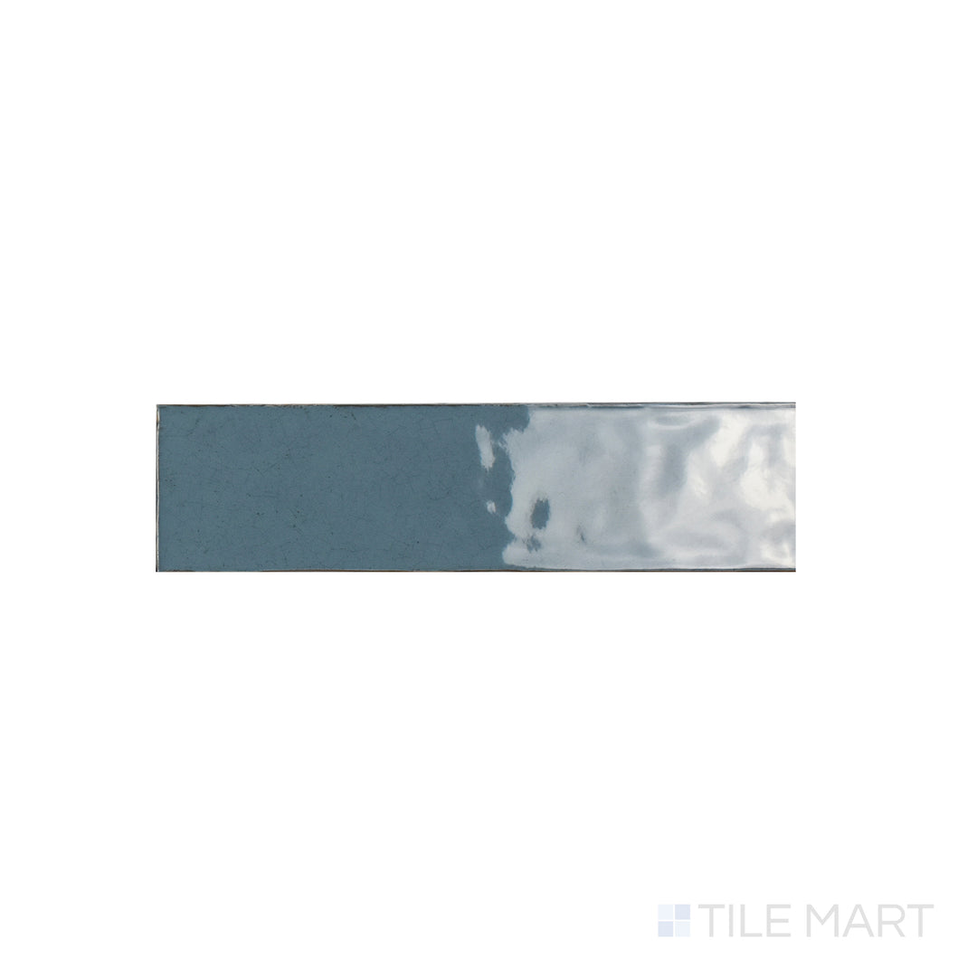 A focused close-up of Maiolica Blue Steel 3x12 Bright Ceramic Tile, highlighting its deep steel-blue shade with a sleek, polished surface. The glossy finish amplifies richness and shine.