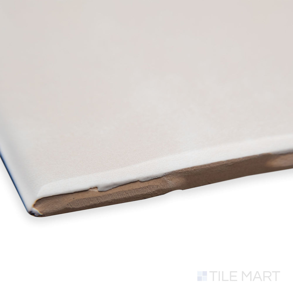 A close-up corner perspective of Maiolica Biscuit 3X6 bright ceramic bullnose, highlighting its warm neutral tone, curved edge detail, and polished surface.