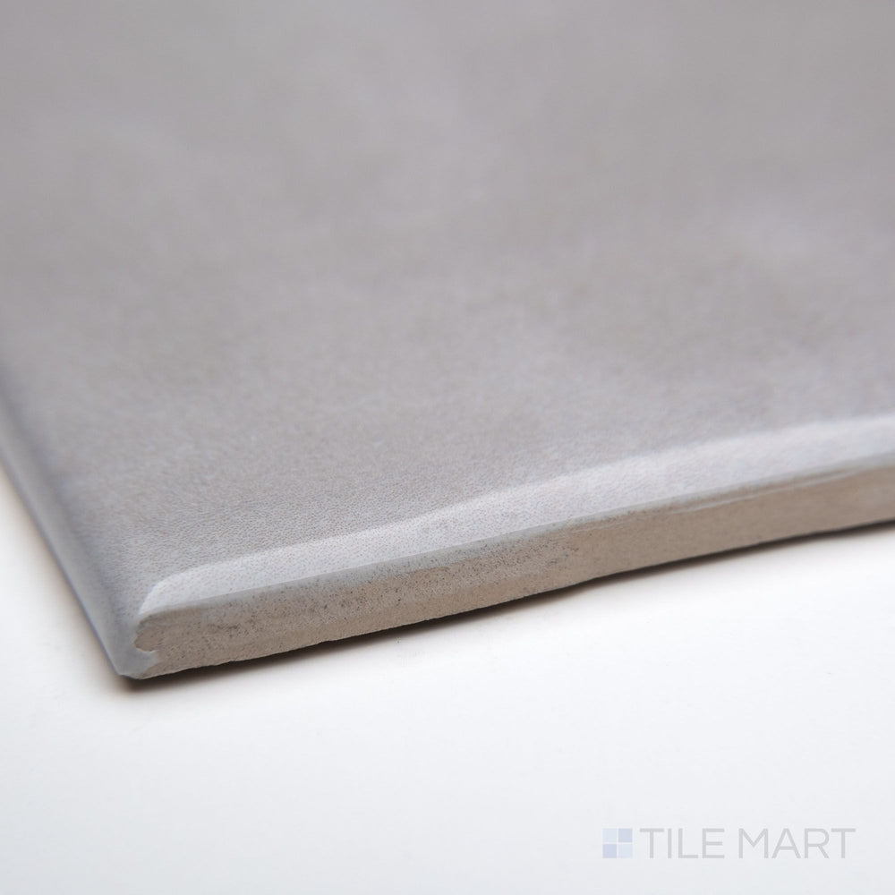 A corner view of Maiolica Tender Gray 3X6 bright ceramic bullnose, emphasizing its subtle gray shade, smooth bullnose edge, and reflective ceramic finish.