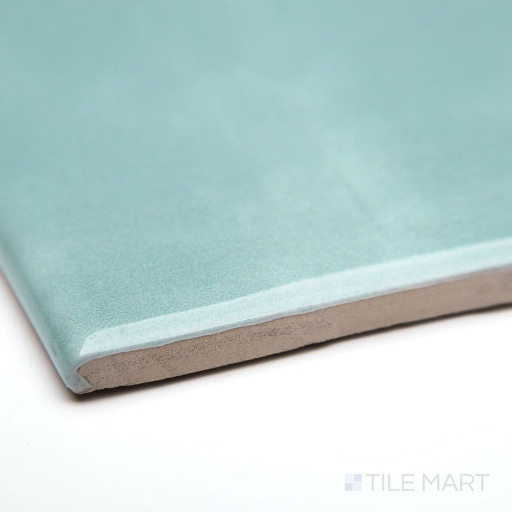 A close-up of Maiolica Aqua 3X6 bright ceramic bullnose, showcasing its vibrant blue-green color, sleek curved edge, and glossy ceramic glaze.