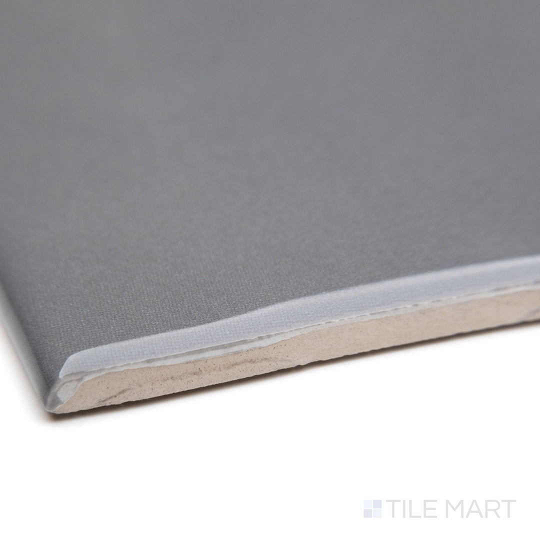 A detailed corner perspective of Maiolica Taupe 3X6 bright ceramic bullnose, focusing on its warm taupe hue, rounded bullnose profile, and polished surface.