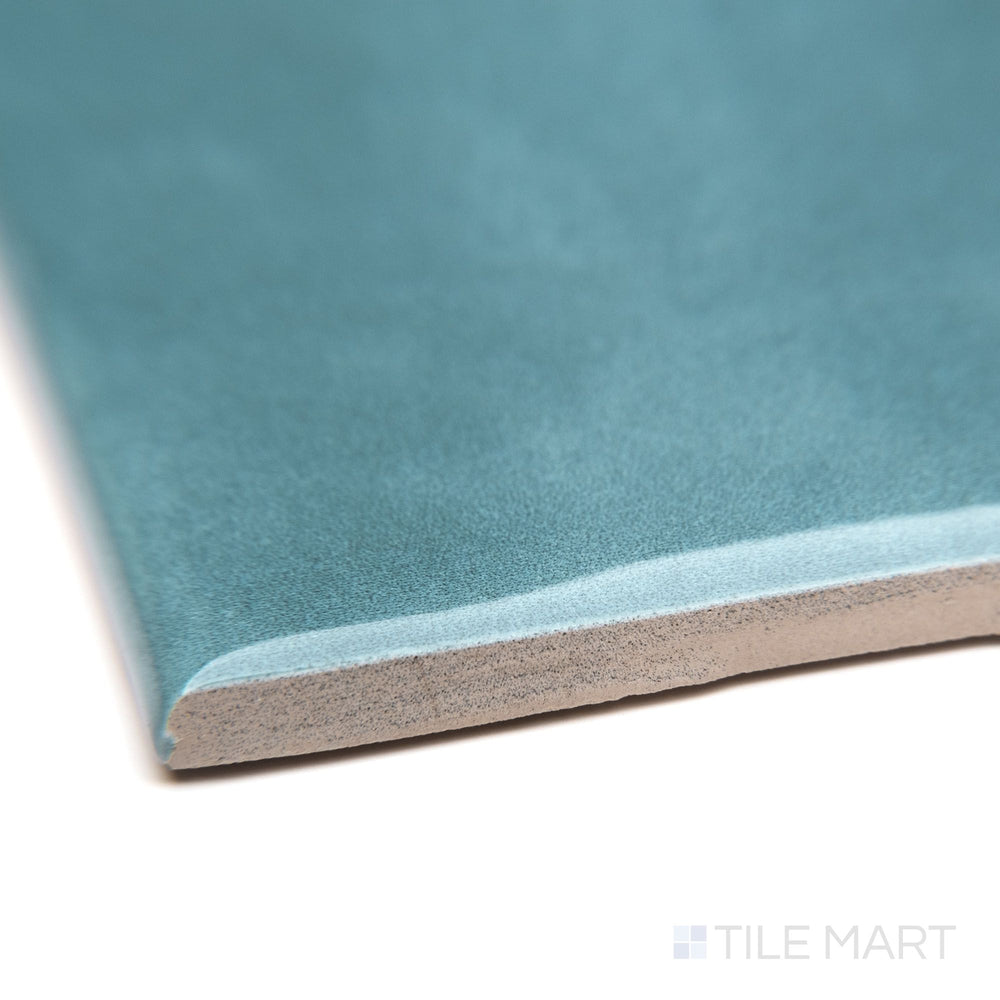 A zoomed-in corner shot of Maiolica Blue Steel 3X6 bright ceramic bullnose, featuring its deep blue-gray color, curved profile, and glossy sheen.