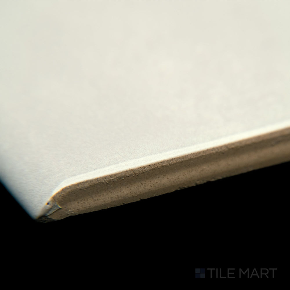 A detailed edge view of Maiolica Biscuit 3X10 bright ceramic bullnose, emphasizing its warm beige tone, well-defined bullnose curve, and polished texture.