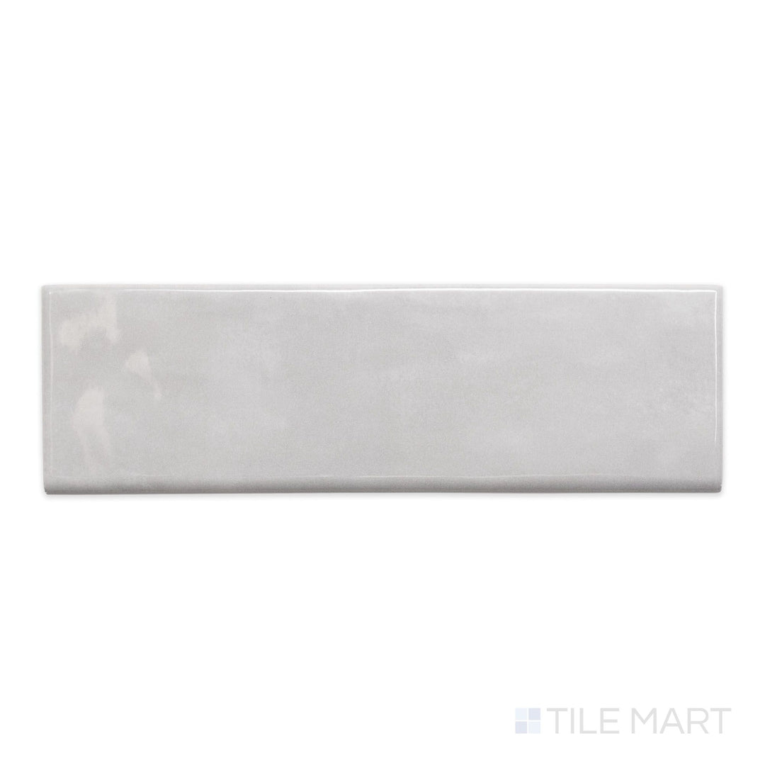 A top-down view of Maiolica Tender Gray 3x10 bright ceramic bullnose, showcasing its muted gray shade and glossy, refined finish.