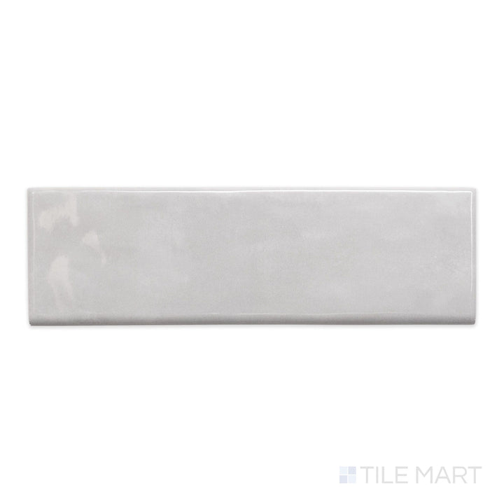A top-down view of Maiolica Tender Gray 3x10 bright ceramic bullnose, showcasing its muted gray shade and glossy, refined finish.